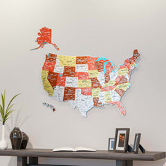 Terracotta UV printed metal USA wall map with state names above a dark console with a vase and framed photos, wide view