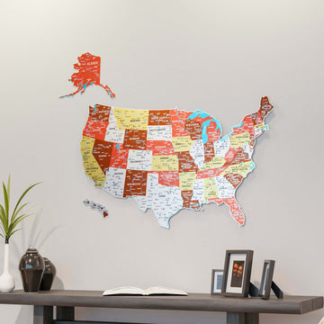 Terracotta UV printed metal USA wall map with state names above a dark console with a vase and framed photos, wide view