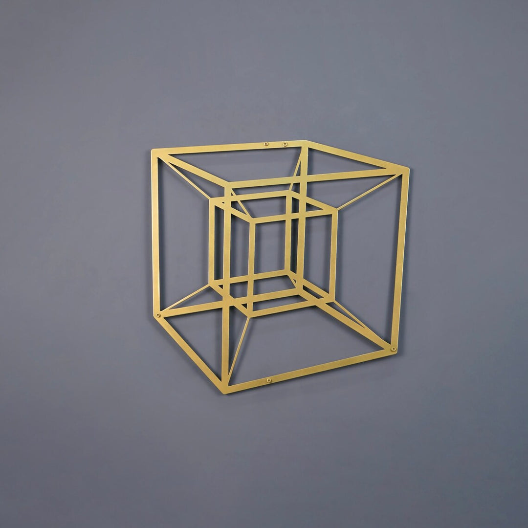 Gold tesseract cube metal wall art on a grey wall, front view
