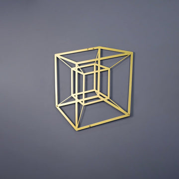 Gold tesseract cube metal wall art on a grey wall