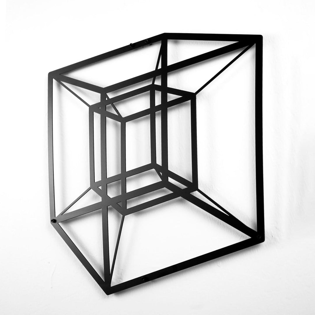 Black tesseract cube metal wall art at an angle with its shadow