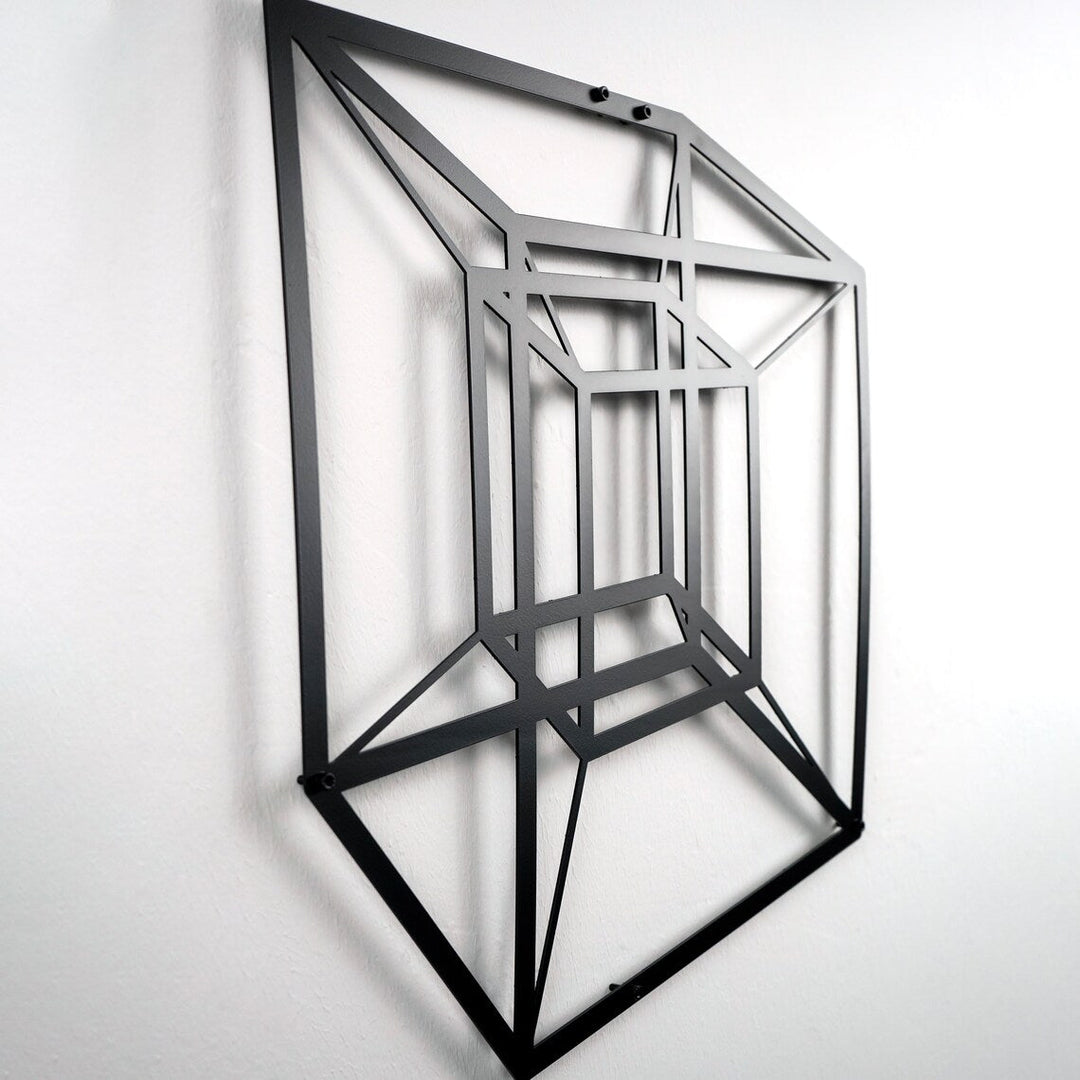 Black tesseract cube metal wall art seen from below, shadow on the wall