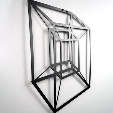 Black tesseract cube metal wall art seen from below, shadow on the wall