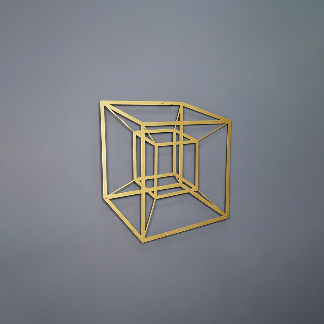 Gold tesseract cube metal wall art on a grey wall, side view