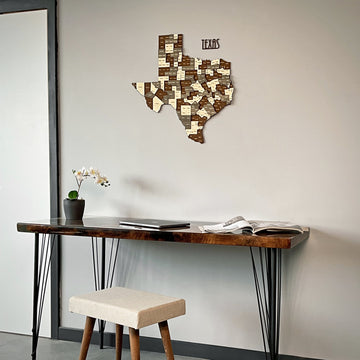 Texas layered wood map above a console desk and upholstered stool, seen from a lower left angle