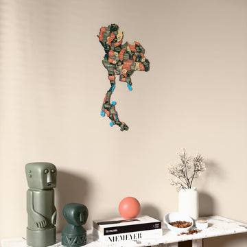 Sage Thailand wooden wall map on a beige wall above a console with figurines
