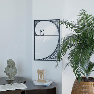 Black Fibonacci spiral metal wall art on a white wall beside a palm and a stone bust, wide view