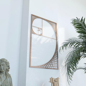 Copper Fibonacci spiral metal wall art, angled view with palm fronds at the right and a stone bust at the lower left