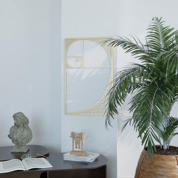 Gold Fibonacci spiral metal wall art on a white wall beside a palm and a stone bust, wide view