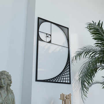 Black Fibonacci spiral metal wall art, angled view with palm fronds at the right and a stone bust at the lower left
