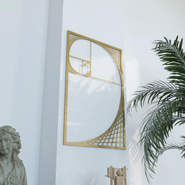 Gold Fibonacci spiral metal wall art, angled view with palm fronds at the right and a stone bust at the lower left