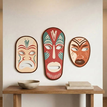 Tribal masks metal wall art set above a wooden table on a light wall