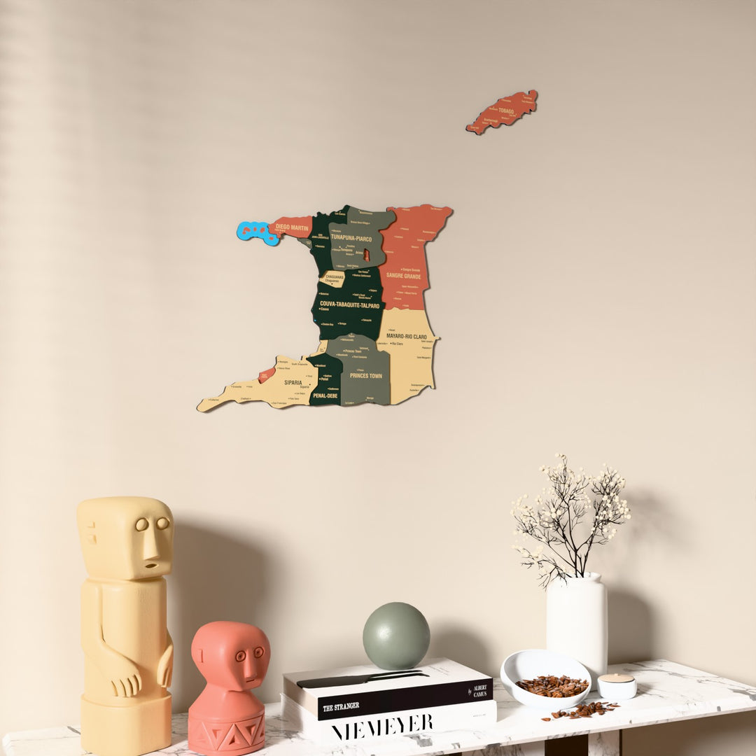 Sage Trinidad and Tobago wooden wall map on a beige wall above a console with figurines