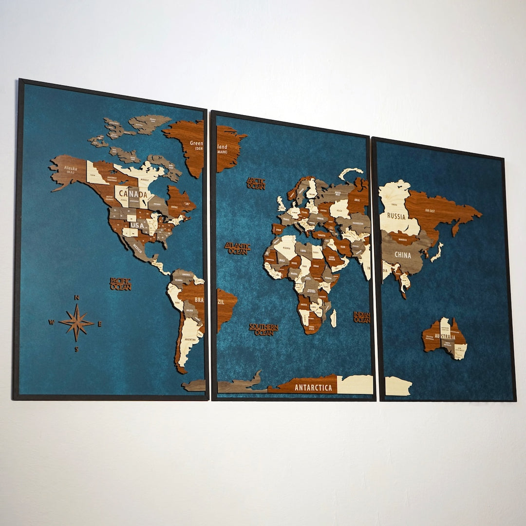 Three-panel wooden world map with a compass rose, angled view from the left on a white wall