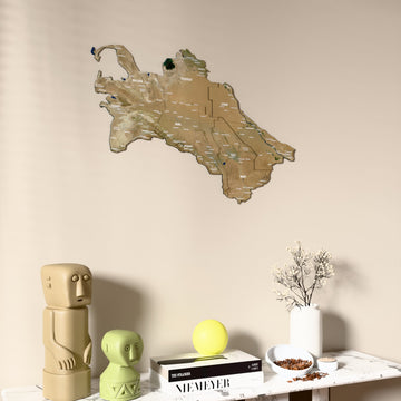 Satellite Turkmenistan wooden wall map on a beige wall above a console with figurines