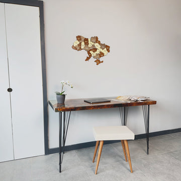 Small Ukraine wooden wall map on a gray wall beside a dark door, with a desk and stool below