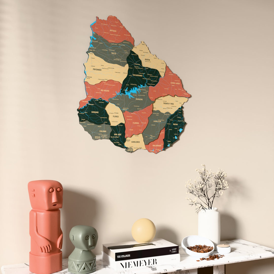 Sage Uruguay wooden wall map on a beige wall above a console with figurines