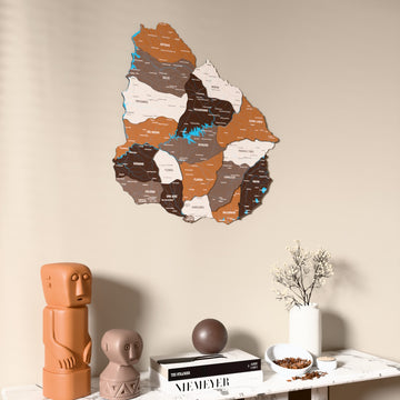 Soil Uruguay wooden wall map on a beige wall above a console with figurines