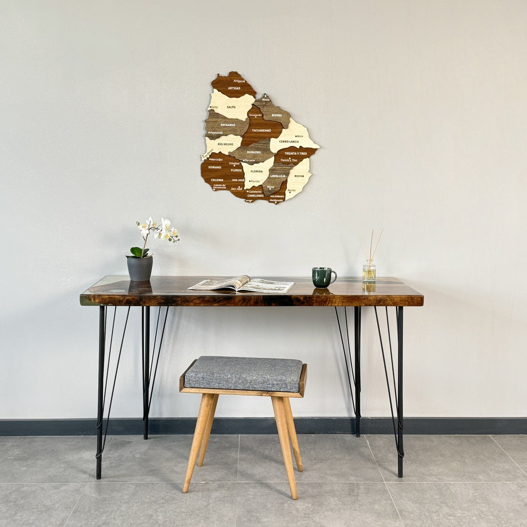 Wooden Uruguay map above a hairpin-leg desk and gray stool, wide view of the wall