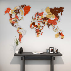 Terracotta metal world map in red, mustard and brown above a dark console with framed photos and a plant