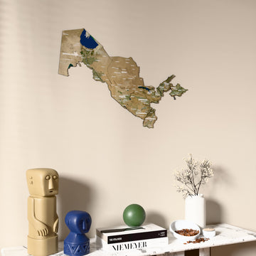 Satellite Uzbekistan wooden wall map on a beige wall above a console with figurines