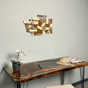 Washington State wooden wall map above a live-edge resin table with an orchid
