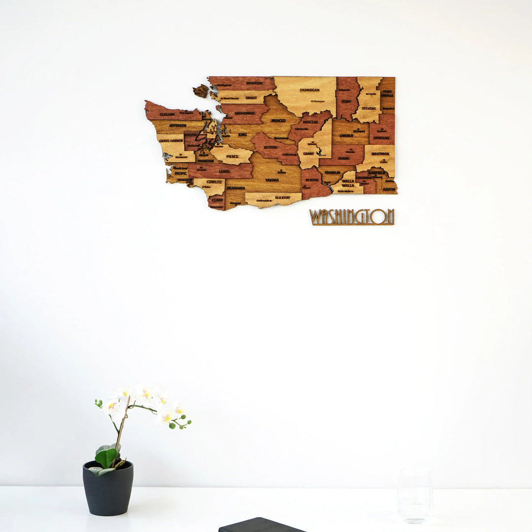 Washington wooden wall map above a white surface with an orchid at the bottom, lettering below the map