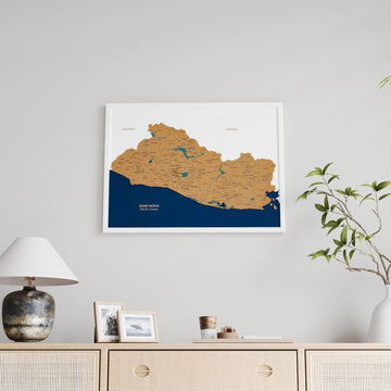 Small white framed El Salvador cork map above a sideboard with a vase, wide view