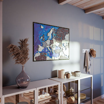 Nimbus wooden Europe map on a gray wall above a glass-front shelf unit with dried grass in a vase