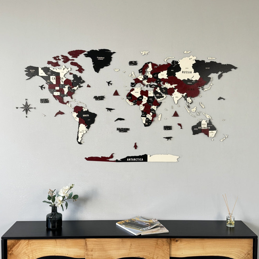 Burgundy, black and cream wooden world map above a black sideboard with a vase, wide view