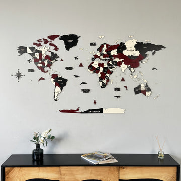 Burgundy, black and cream wooden world map above a black sideboard with a vase, wide view