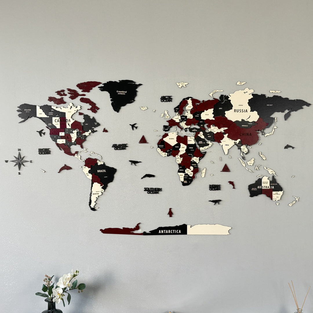 Burgundy wooden world map on a gray wall with a compass rose, front close view