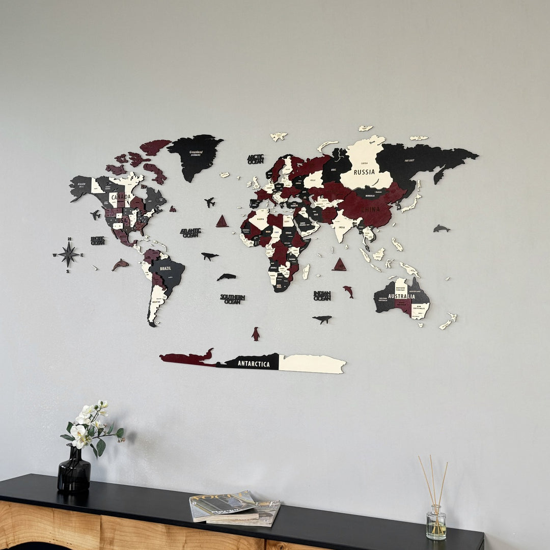 Burgundy wooden world map above a black sideboard, mid-distance view with white flowers at lower left