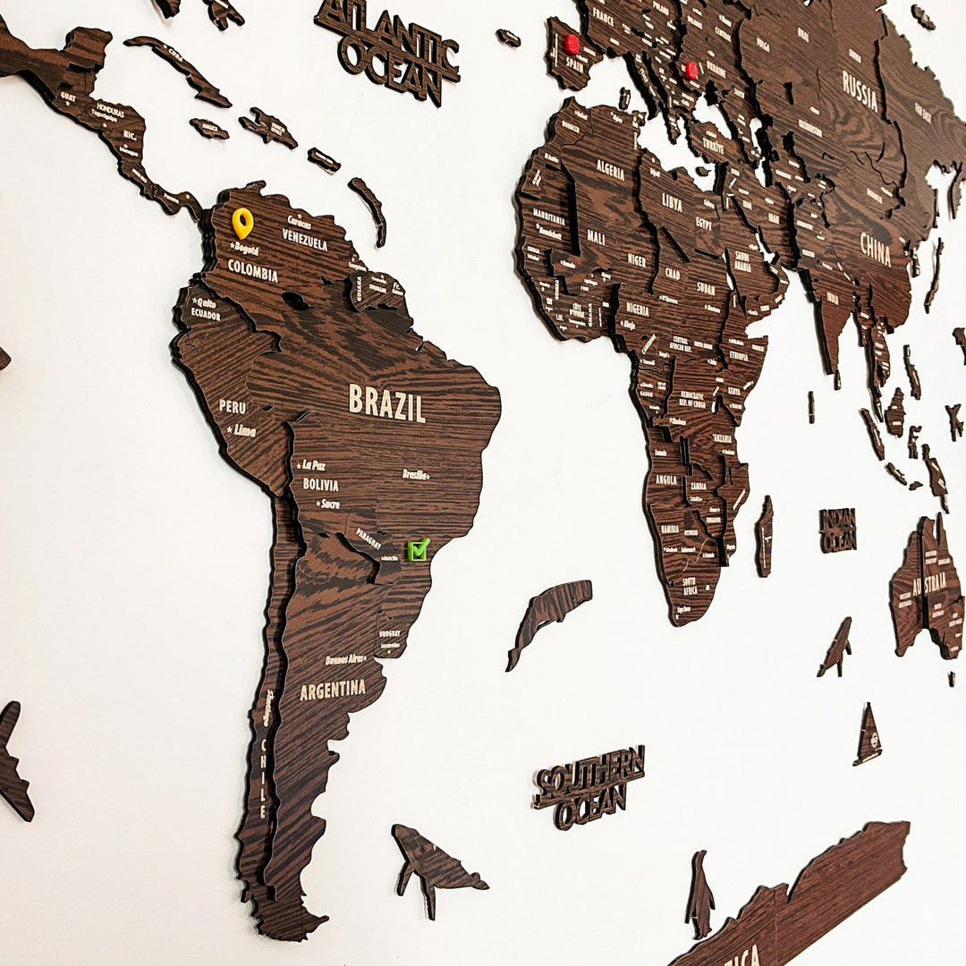 Close-up of South America with Colombia and Brazil pins on the dark brown wooden world map