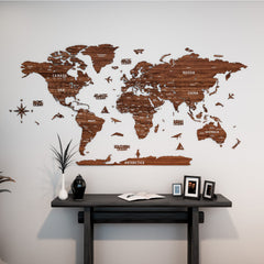 Light brown wooden world map with country names above a dark console table with framed photos