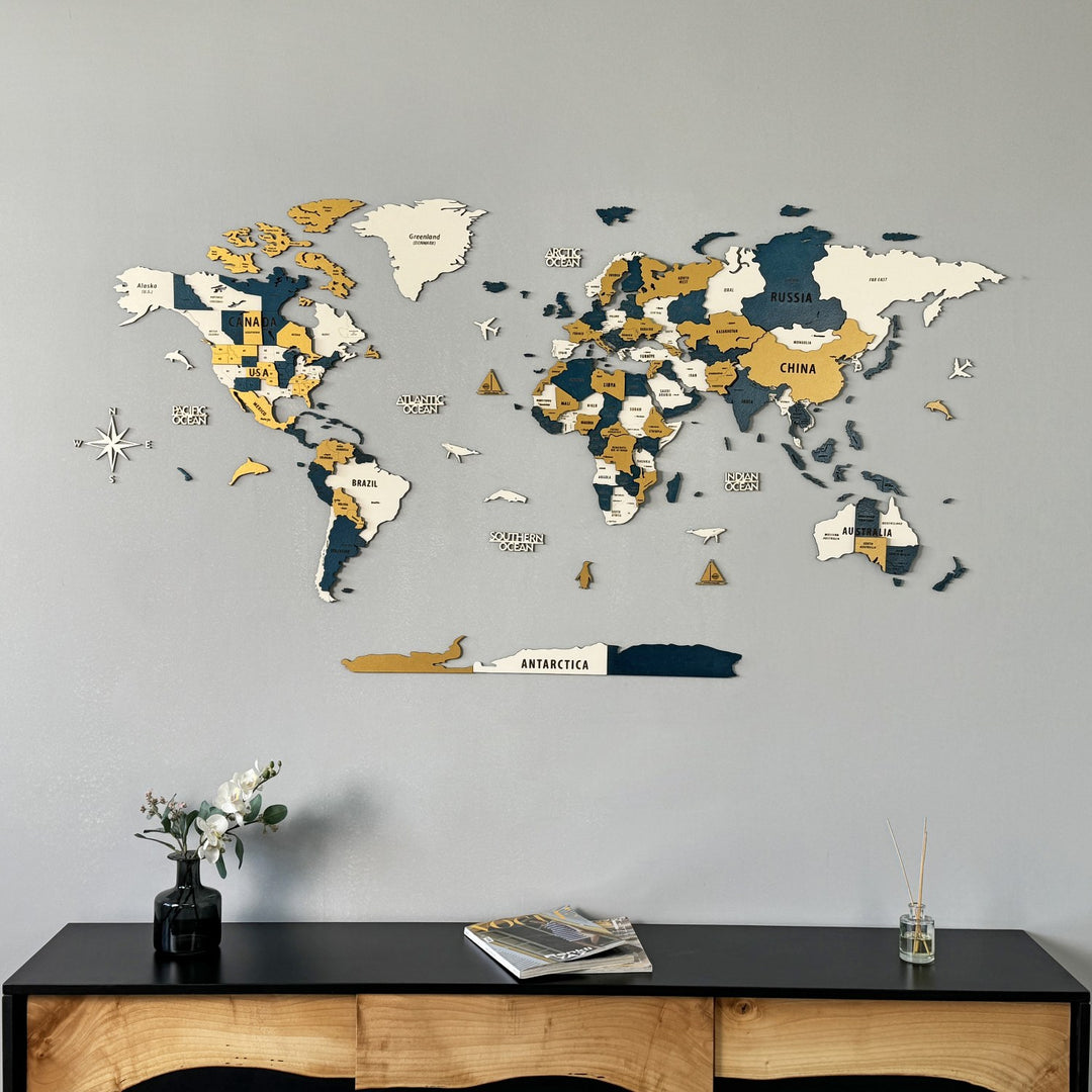 Yellow and navy wooden world map on a gray wall above a black sideboard with a vase, wide view