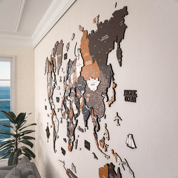 Angled view of the Soil wooden world map along a living room wall with a plant and window