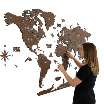 Large light brown wooden world map with a compass rose, a woman pointing to Africa