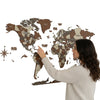 Woman pointing at a wooden world map on a white background