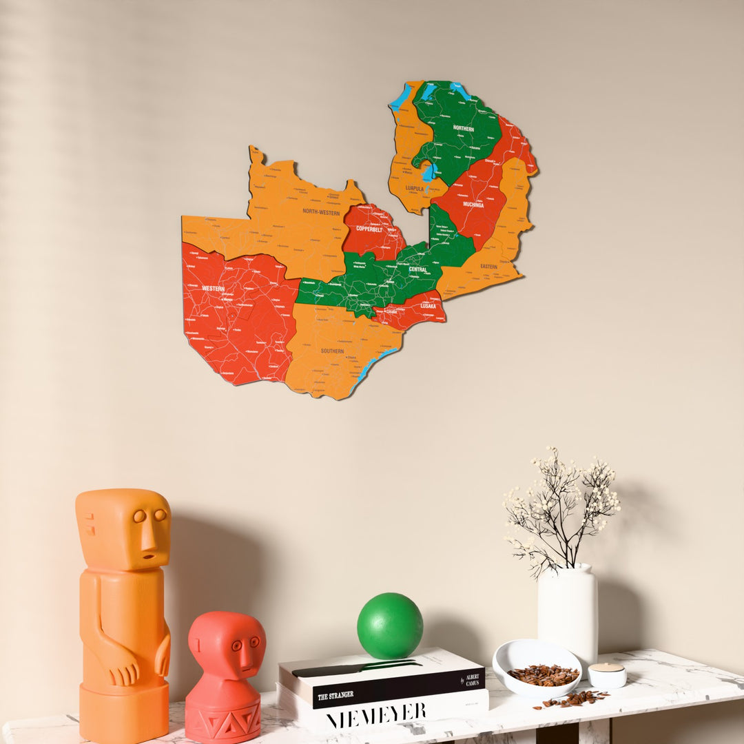 Flag colored Zambia wooden wall map on a beige wall above a console with figurines