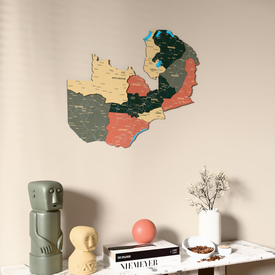 Sage Zambia wooden wall map on a beige wall above a console with figurines