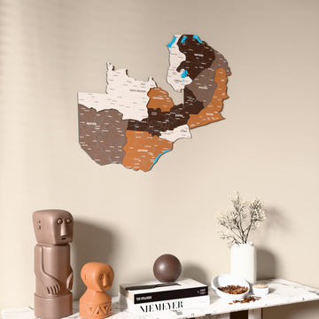 Soil Zambia wooden wall map on a beige wall above a console with figurines