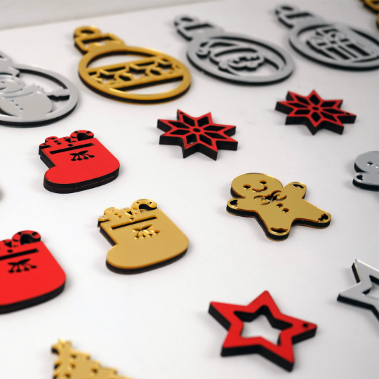 Close-up of red wooden and gold mirror acrylic Christmas ornaments: stocking, gingerbread man, snowflake and star