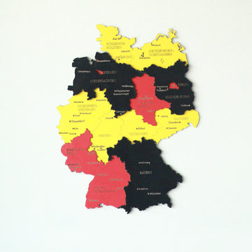 Flag-colored wooden Germany map in black, red and yellow from Schleswig-Holstein down to Bavaria on a light wall