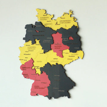 Full view of the black, red and yellow wooden Germany map on a pale wall with state names and city labels