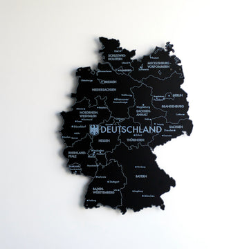 Black UV printed metal Germany map with state and city names, front view on a white wall