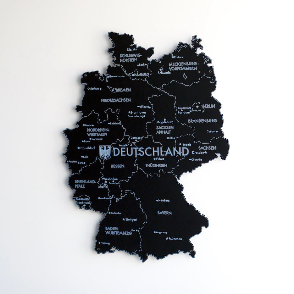 Black UV printed metal Germany map with city names, slightly turned view on a white wall