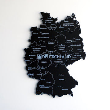 Black UV printed metal Germany map with city names, slightly turned view on a white wall